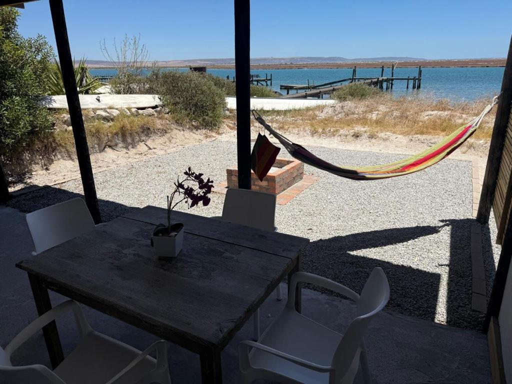 a table and chairs with a hammock and the beach at Bergriver Nest in Velddrif