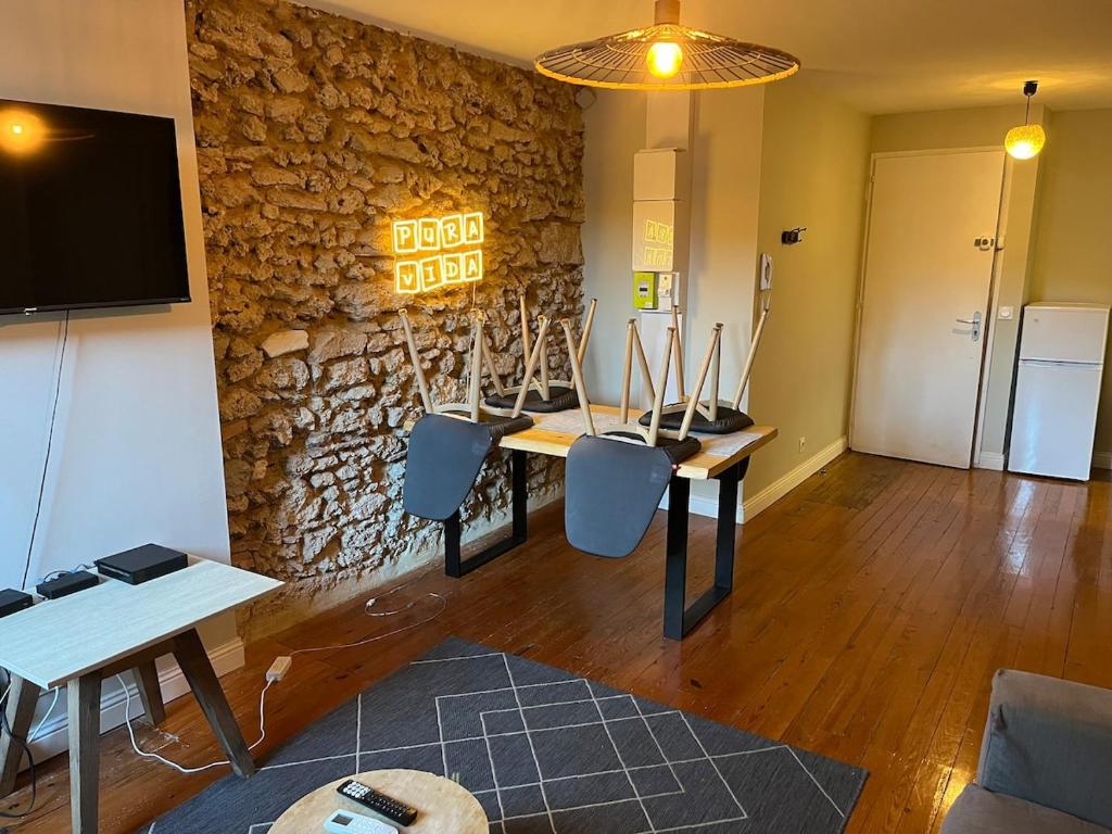 a room with a table and chairs and a stone wall at Le Cocon Authentique in Mont-de-Marsan
