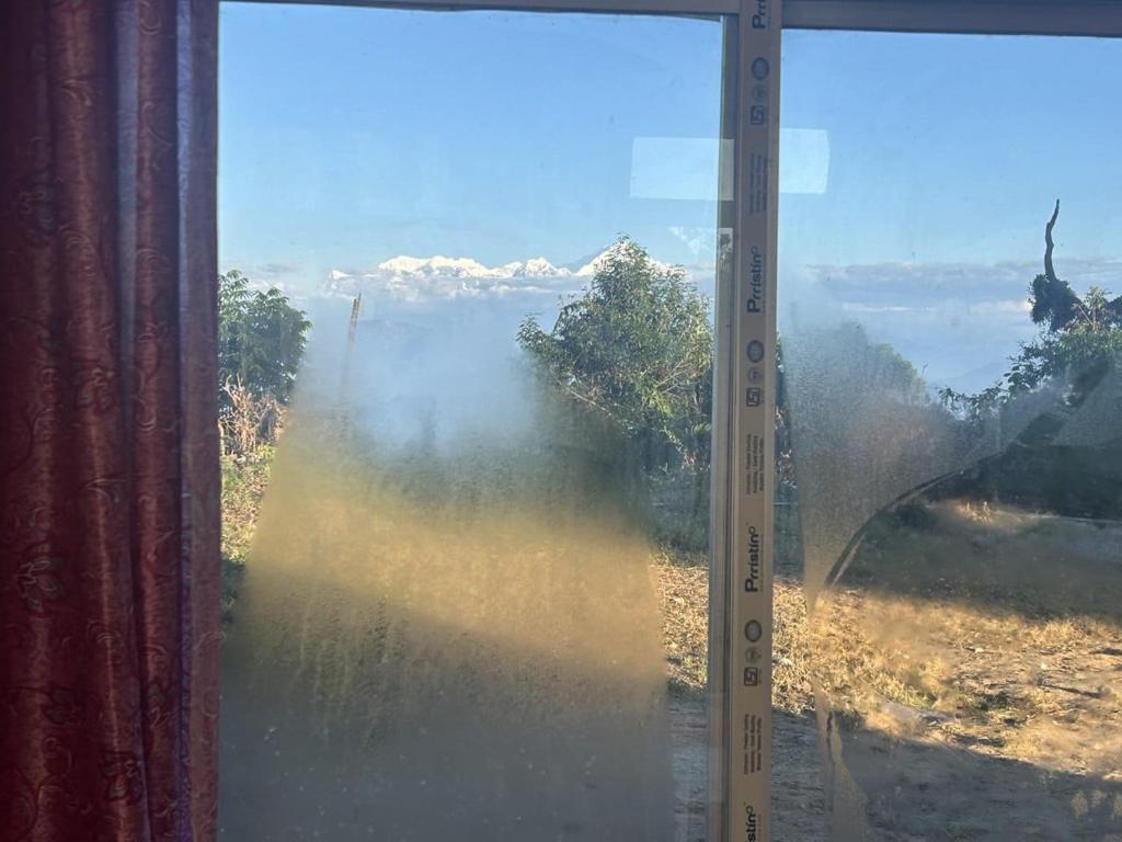 a glass window with a view of a field at Silverberry Homestay in Rishop