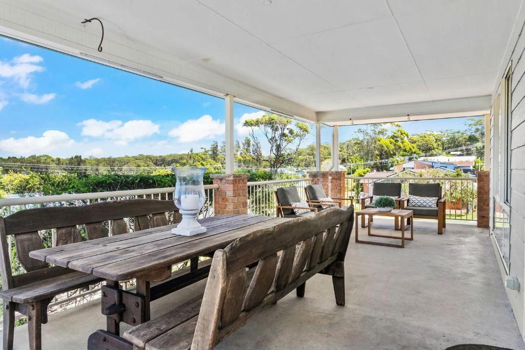 een patio met een houten tafel en banken op een balkon bij Neptune's at Manyana in Manyana