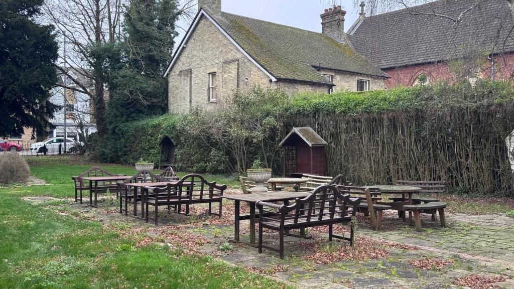 a group of wooden tables and benches in front of a building at The March Hotel in March