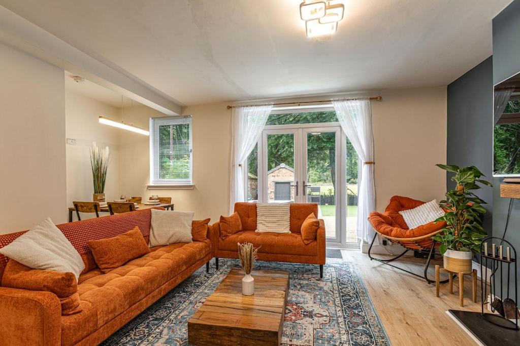 a living room with orange couches and chairs at Yarrow cottage in Broadmeadows