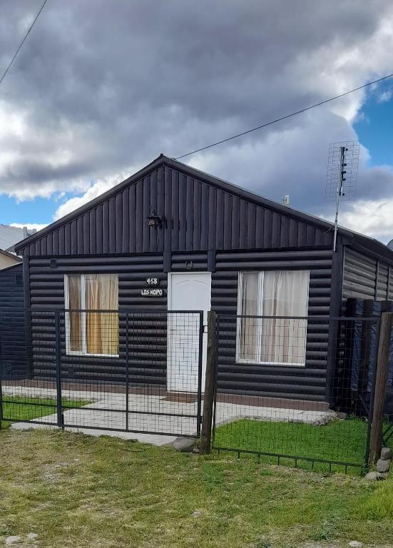 a black house with a fence in front of it at Los Nopo in Trevelín