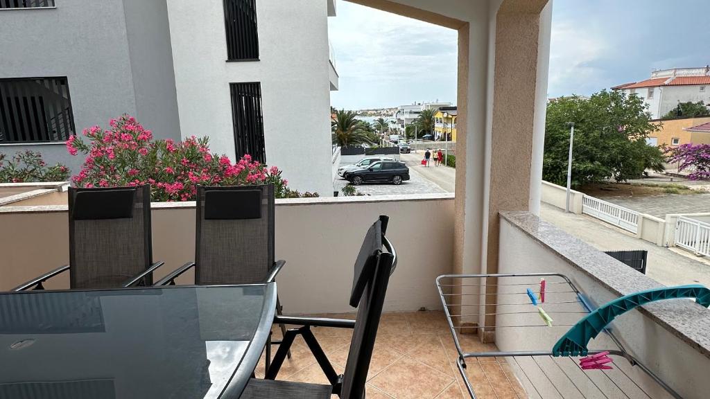 a balcony with a glass table and chairs on a balcony at Apartman a tengernél in Vir