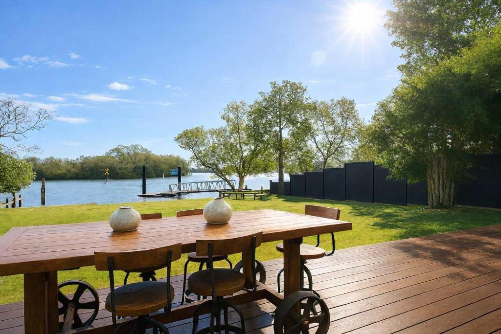 einen Holztisch und Stühle auf einer Terrasse in der Nähe des Wassers in der Unterkunft Waterfront Coomera Escape in Gold Coast
