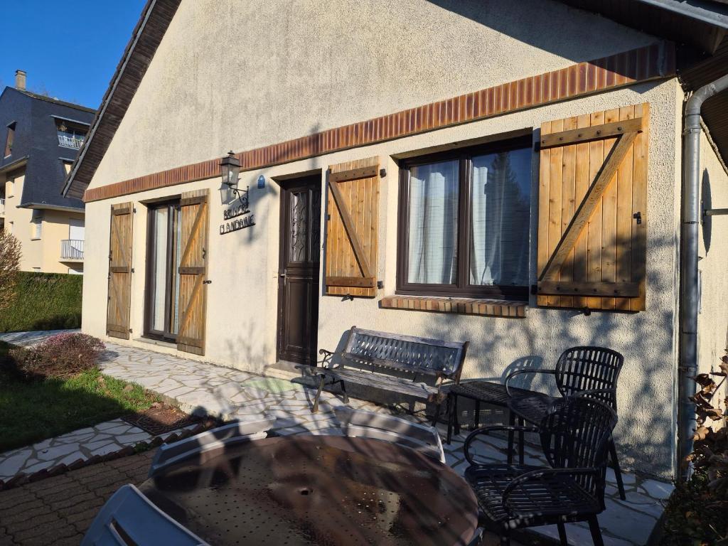 een huis met houten deuren en een tafel en stoelen bij BRUYERE D'ANDAINE in Bagnoles de l'Orne