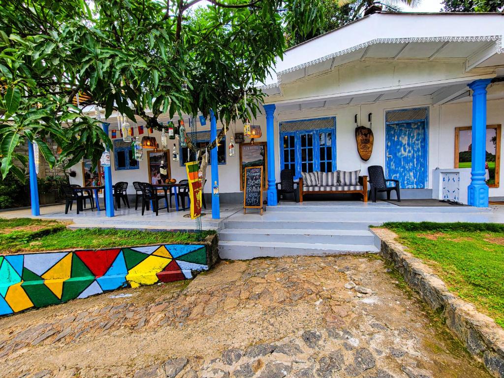 a house with a porch with a bench and tables at Ella Ceylon Homies Hostel in Ella