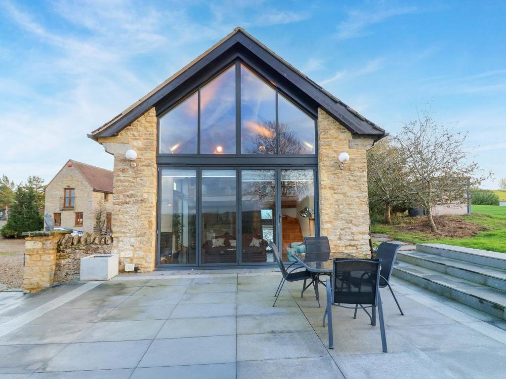 a house with glass windows and a table and chairs at The Lodge Lodge Farm in Bedford