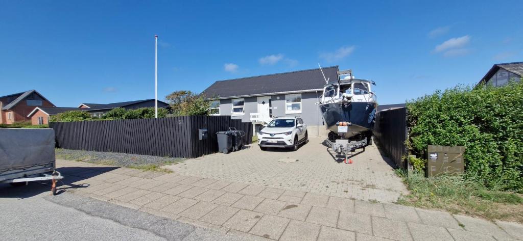un'auto e una barca parcheggiate in un vialetto di Fihermans House Joanna2 a Hirtshals