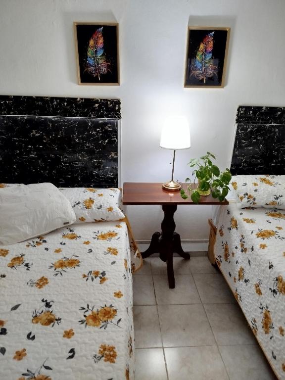 a bedroom with two beds and a desk with a table at Hotel El Almendro in Pedernales