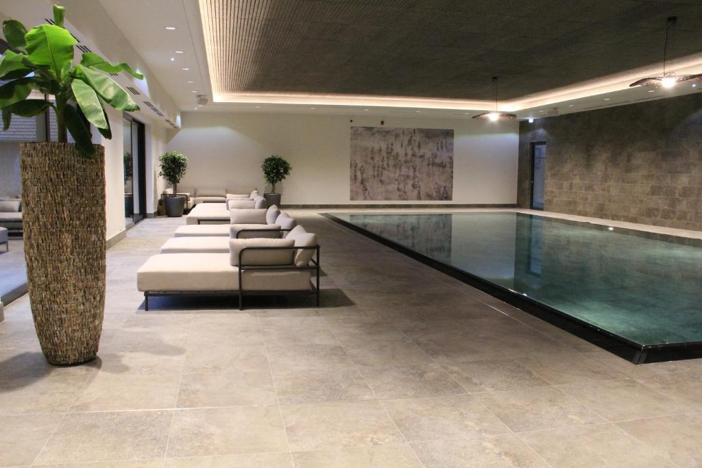 een zwembad in een gebouw met stoelen en een tafel bij Farmer Hotel Basedow & Spa in Basedow