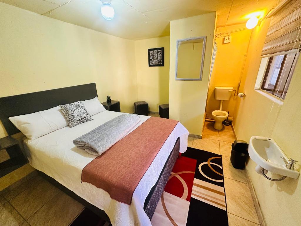 a bedroom with a bed and a bathroom with a sink at SleepCozyGuestHouse in Soweto