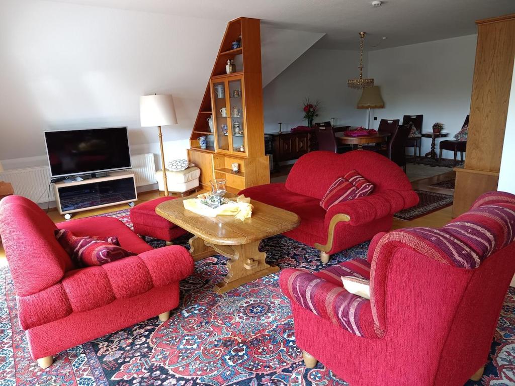 a living room with two red chairs and a table at Ferienwohnung Jansen in Ostrhauderfehn