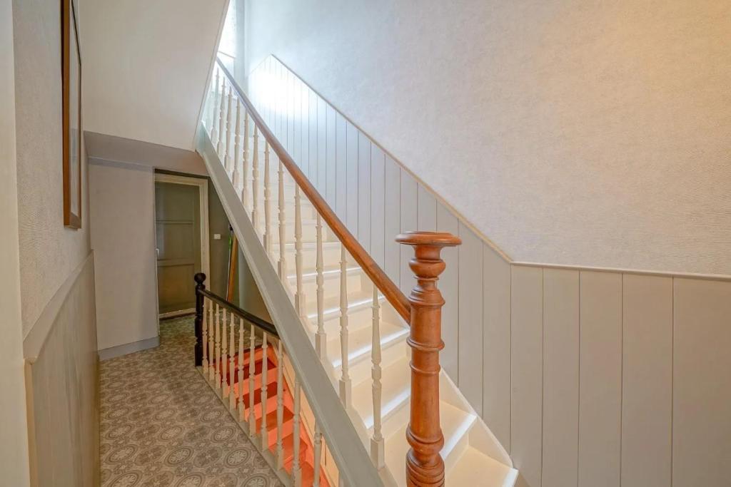 una scala con pareti bianche e ringhiera in legno di Huyze Elise a Ostenda