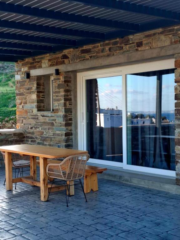 a wooden table and chairs in front of a window at Sea melody tinos 3 in Agios Sostis