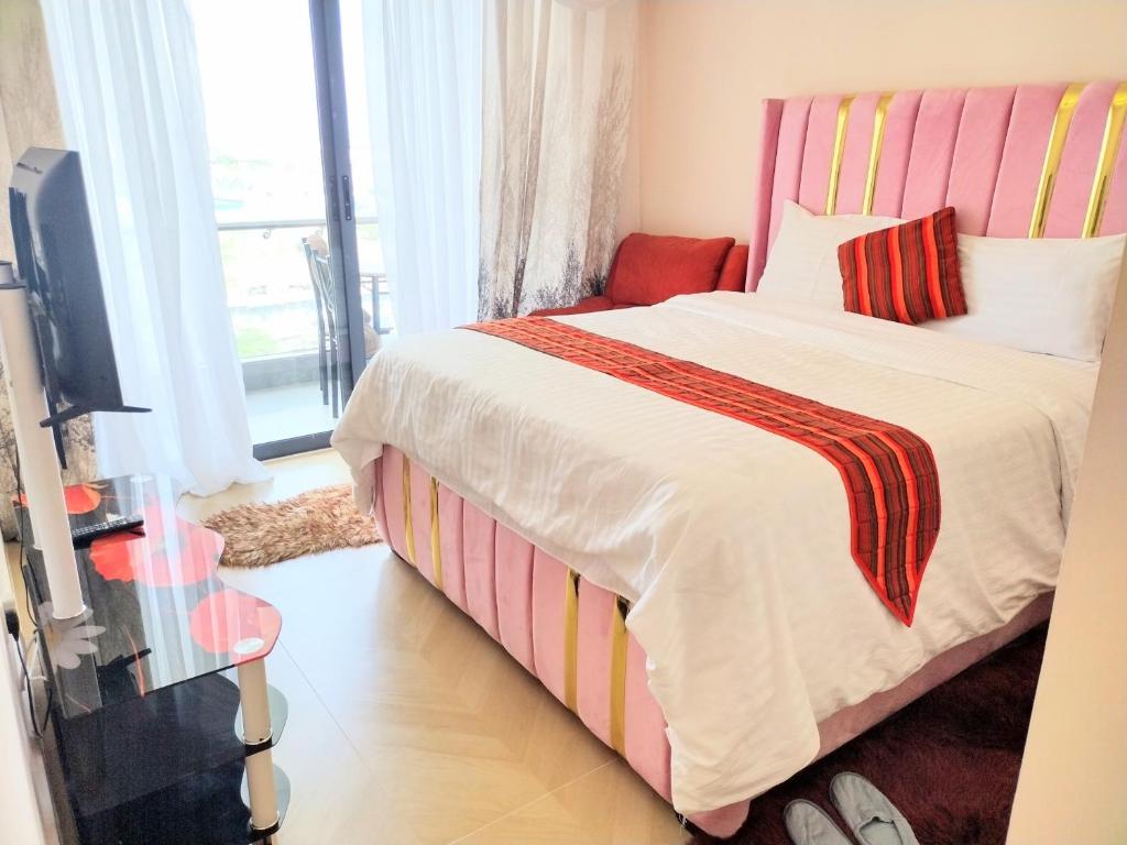 een slaapkamer met een bed met een gestreept hoofdeinde en een tv bij Lenayan at Artesano in Nairobi