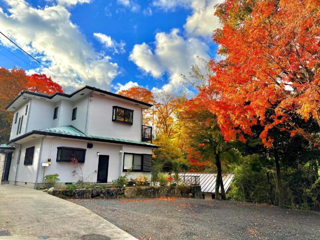 a white house in the fall with trees at 箱根宿燕帰 in Hakone