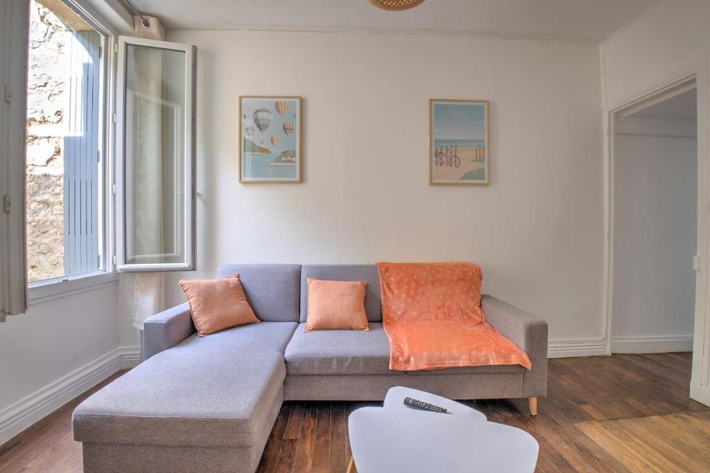 un salon avec un canapé bleu et un coussin orange dans l'établissement L'échappée verte, à Périgueux