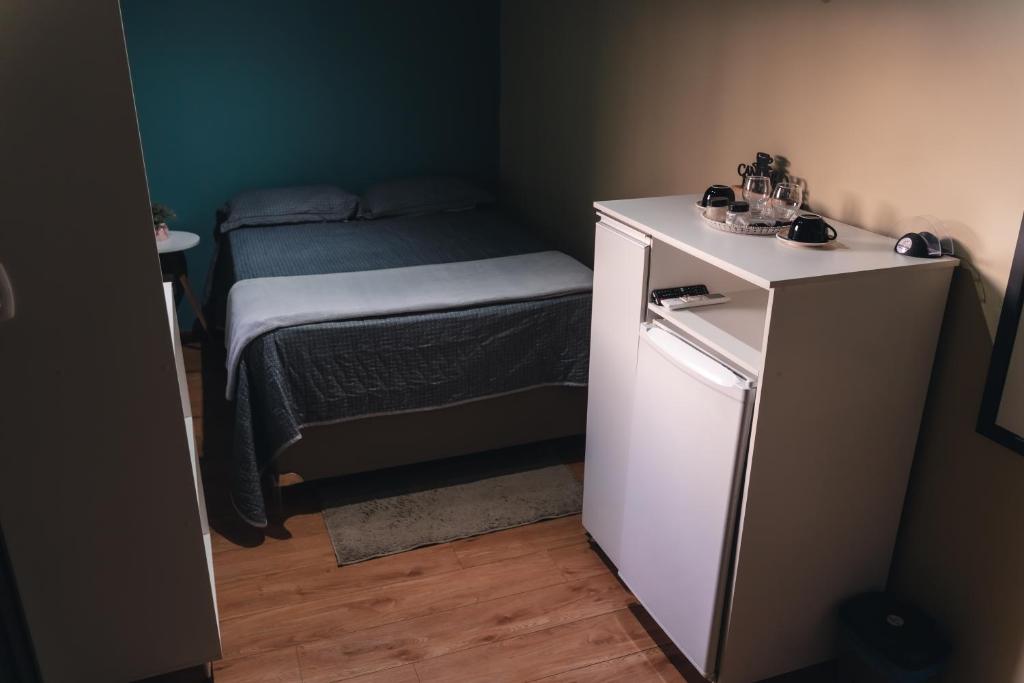 a small room with a bed and a small refrigerator at Mango View - Estúdio Confortável com Piscina - Boa Vista in Boa Vista