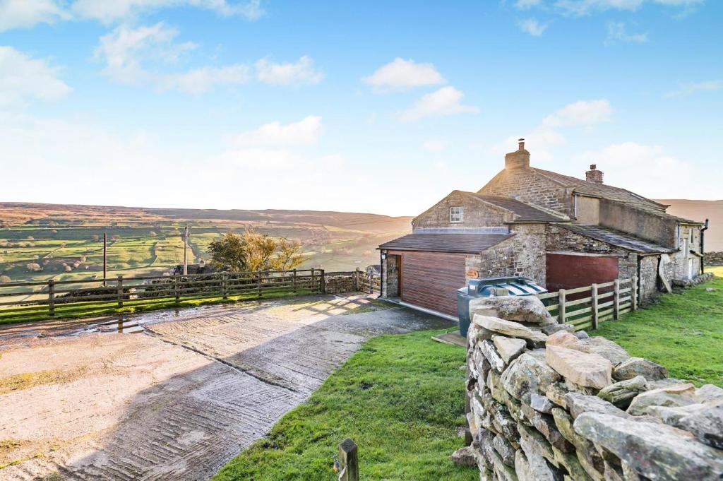 ein altes Steinhaus auf einem Hügel mit einem Zaun in der Unterkunft 3 Bed in Low Row oc-h34097 in Gunnerside