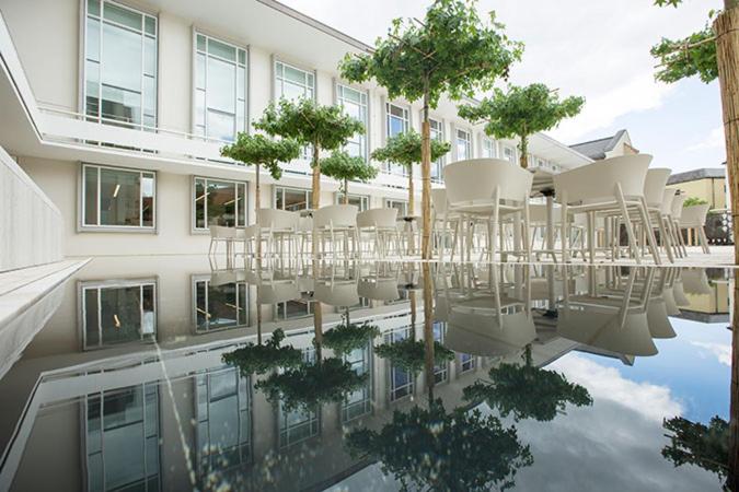 ein Gebäude mit Stühlen und Bäumen in einem Pool aus Wasser in der Unterkunft Burkardushaus, Tagungszentrum am Dom in Würzburg