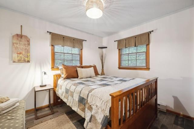 een slaapkamer met een bed en twee ramen bij Laurel Thicket Cottage in Newland