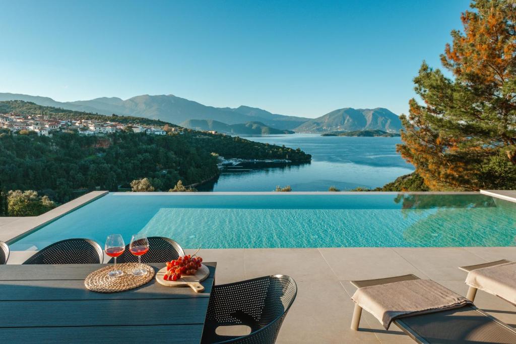 a table with wine glasses and a view of a lake at Kohyli Villas in Meganisi