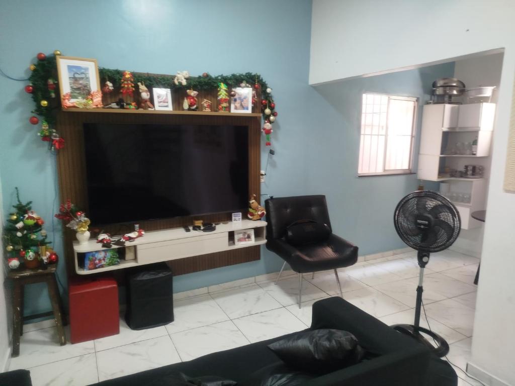 a living room with a large television and a chair at Casa dois quartos 5 pessoas, no centro de Belém in Belém