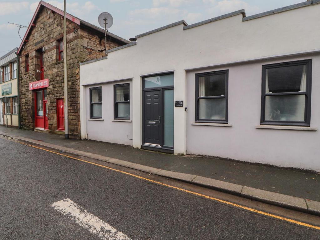 a white building with a black door on a street at 20 Lorton Street in Cockermouth