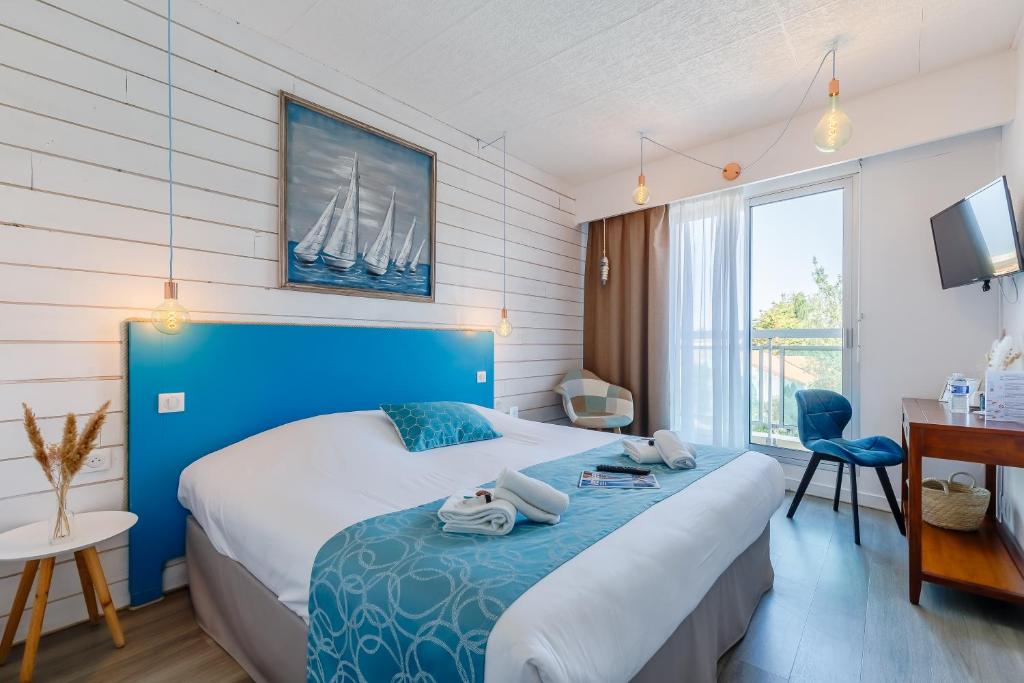 a bedroom with a large bed with a blue headboard at Hotel La Cote Oceane - CLIMATISÉ - Saint Jean de Monts- 250m plage in Saint-Jean-de-Monts