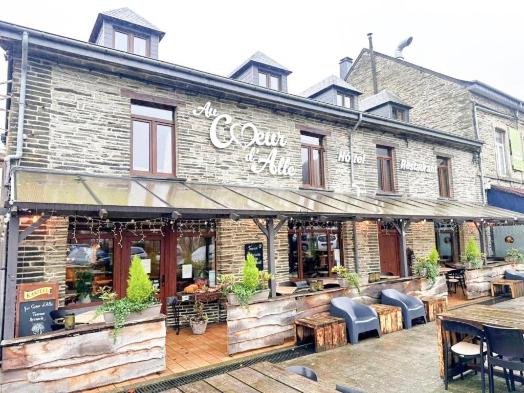 un magasin à l'avant d'un bâtiment en briques avec des tables et des chaises dans l'établissement Au Coeur d'Alle by Belvilla, à Alle