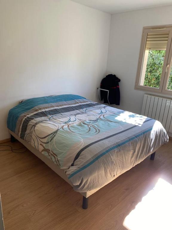 a bed in a white room with a bedspread on it at Chambre de maison de campagne in Uzerche
