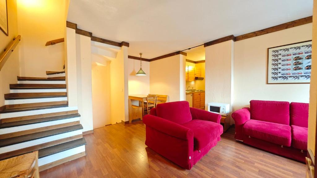 een woonkamer met 2 rode stoelen en een trap bij Hostdomus - Betulle Apartments in Sestriere