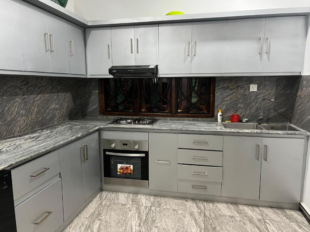 a kitchen with white cabinets and a stove top oven at Kaarasaaram inn in Avarankal
