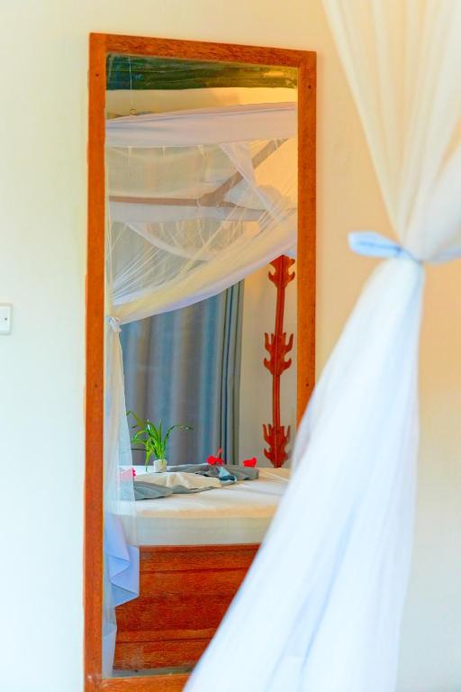a mirror in front of a bedroom with a bed at Bustan in Matemwe