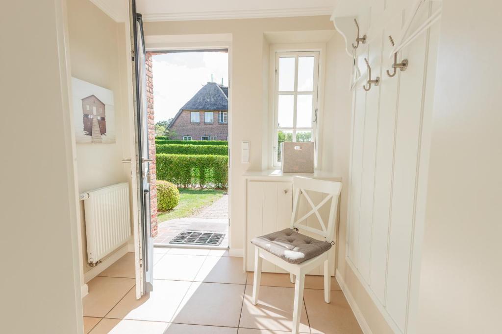 a hallway with a chair and an open door at Haus "Carla Marie" in Hedehusum