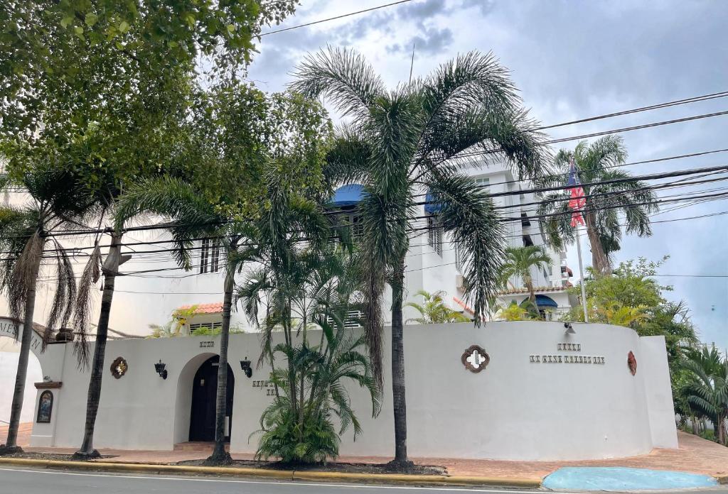 een wit gebouw met palmbomen ervoor bij At Wind Chimes Boutique Hotel in San Juan