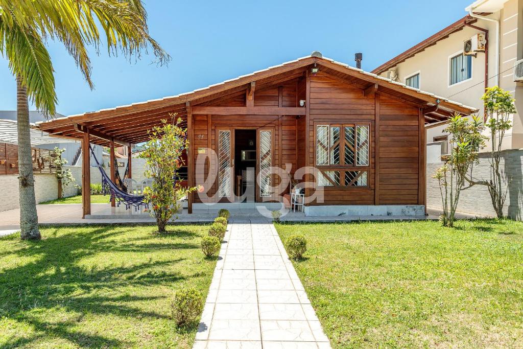 ein Haus mit einem Holzhaus und einem Spielplatz in der Unterkunft Casa Aconchegante – A 200m da praia da Pinheira in Pinheira