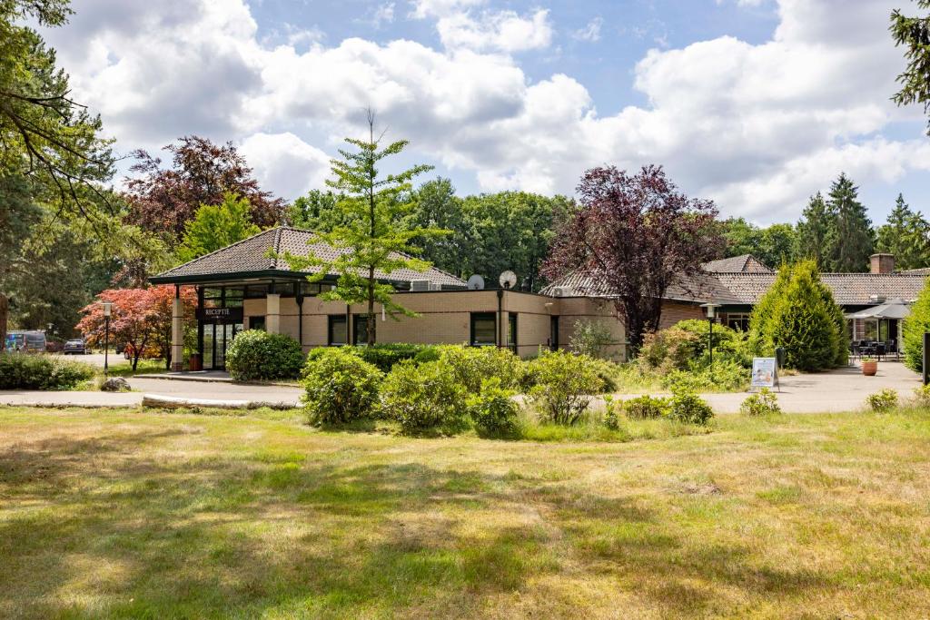 een huis met een tuin ervoor bij Fletcher Hotel Restaurant Victoria-Hoenderloo in Hoenderloo