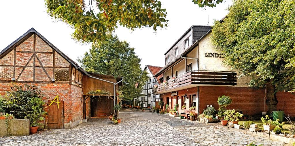 Landgasthaus & Hotel Lindenhof في كونيغسلوتر ام إلم: مبنى من الطوب القديم بجانب مبنى به نباتات