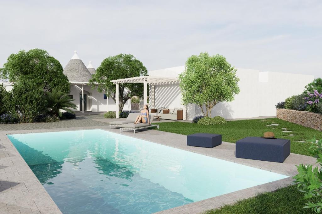 a woman sitting on a couch next to a swimming pool at Pavì Trulli e Suites in Locorotondo