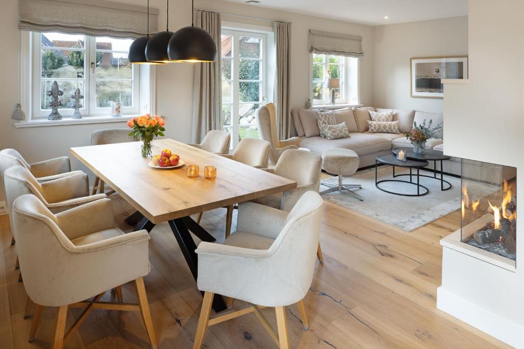 een woonkamer met een tafel, stoelen en een open haard bij Strandhafer in List