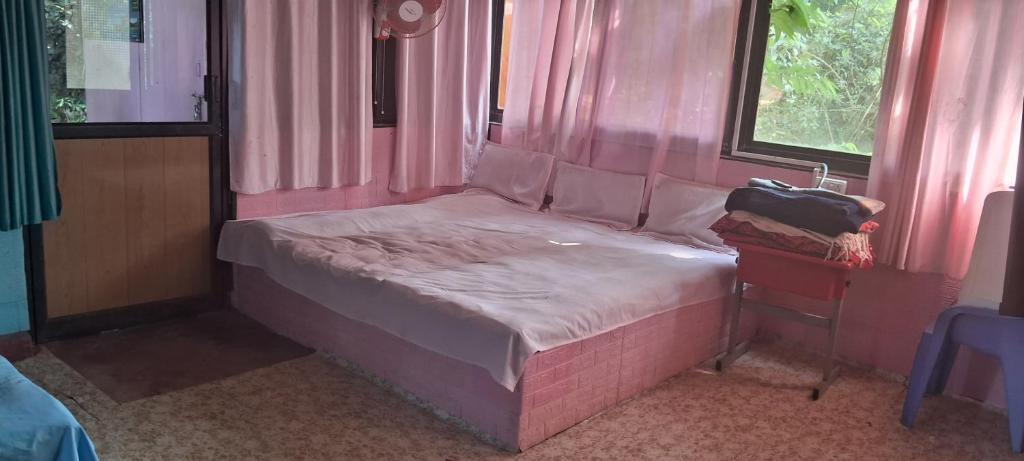 a small pink bed in a room with a window at Shree MAHAGANAPATI ROOMS 6 bed room only for gents in Gokarna