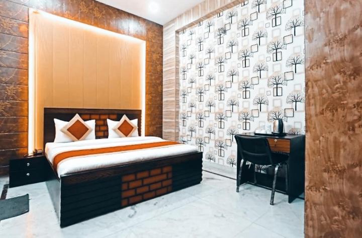 Schlafzimmer mit einem Bett, einem Schreibtisch und einer Wand in der Unterkunft Angel Grand Residency in Greater Noida