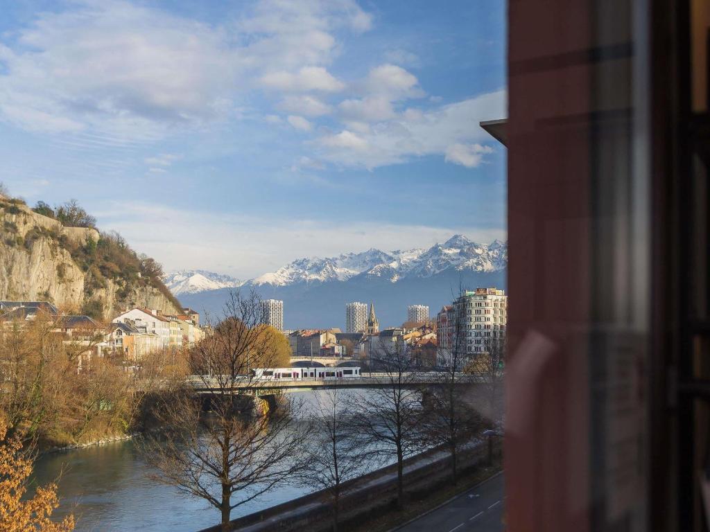 a view of a city with a river and mountains at ibis Grenoble Gare in Grenoble