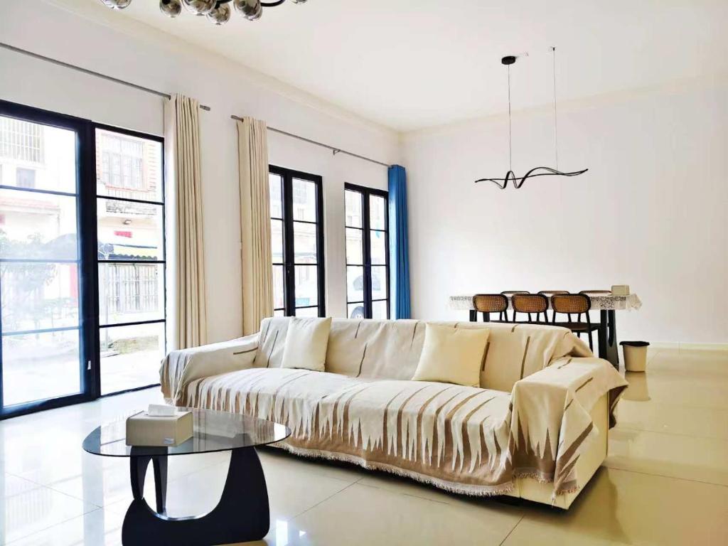 un salon avec un canapé et une table en verre dans l'établissement 闲肆民宿, à Sanya