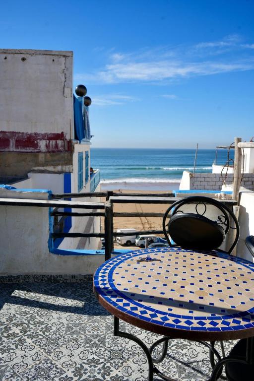 a table and chair on a balcony with the beach at tamazirt surf house in Taghazout