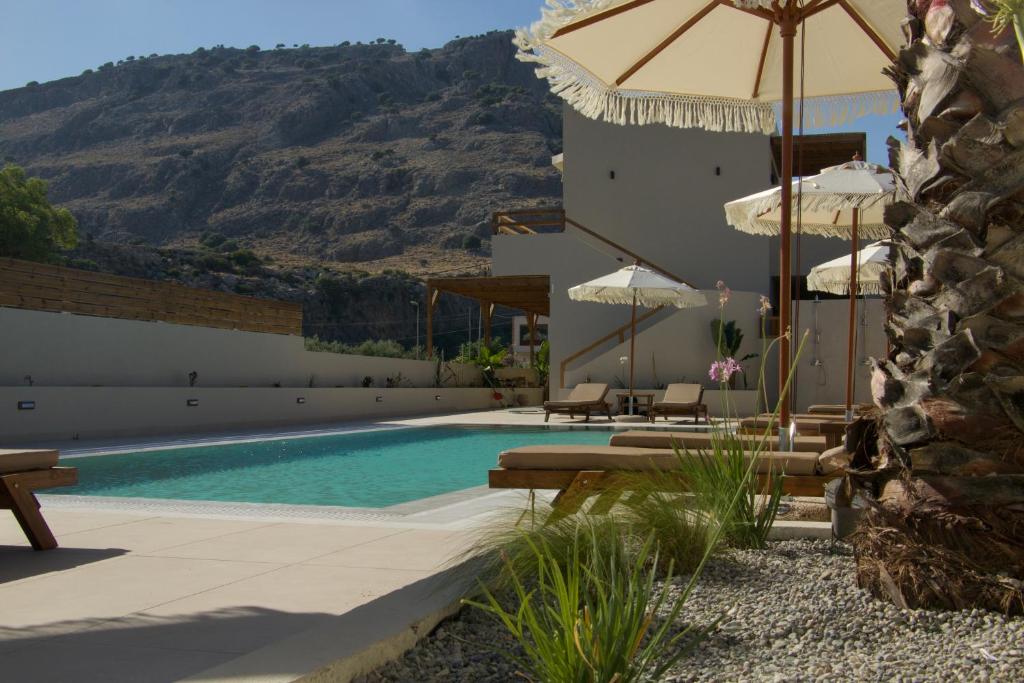 a swimming pool with chairs and umbrellas next to a building at Yucca Calma in Lindos