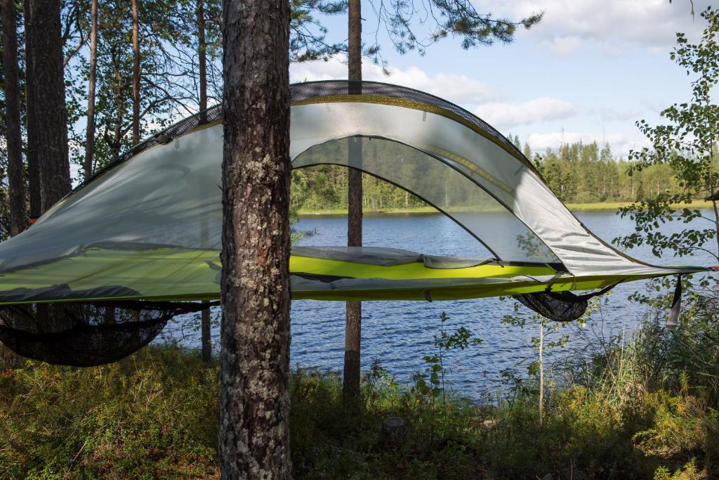 a tent tied to a tree next to a lake at Capture Nordic Wilderness Camp - Baumzelt in Ilomantsi