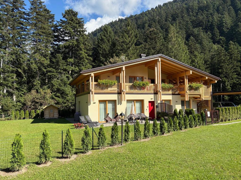 een huis in een veld met een rij bomen bij Chalet Relax Molveno in Molveno